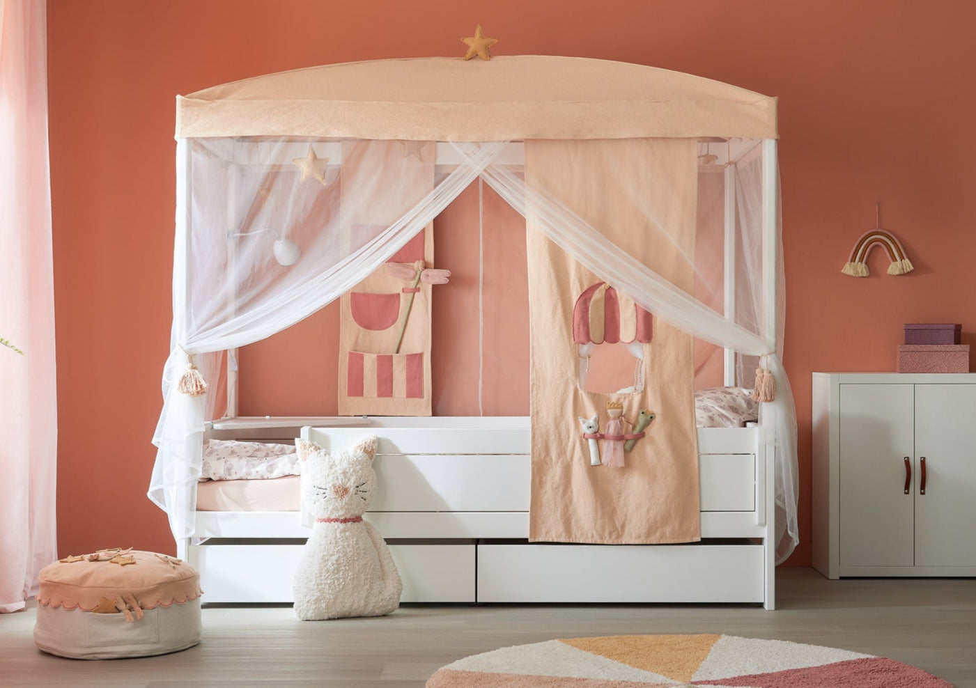 LIFETIME Kidsrooms canopy bed with soft peach and pink curtains, playful fabric details, star decorations, and under-bed storage drawers in a cozy children's room