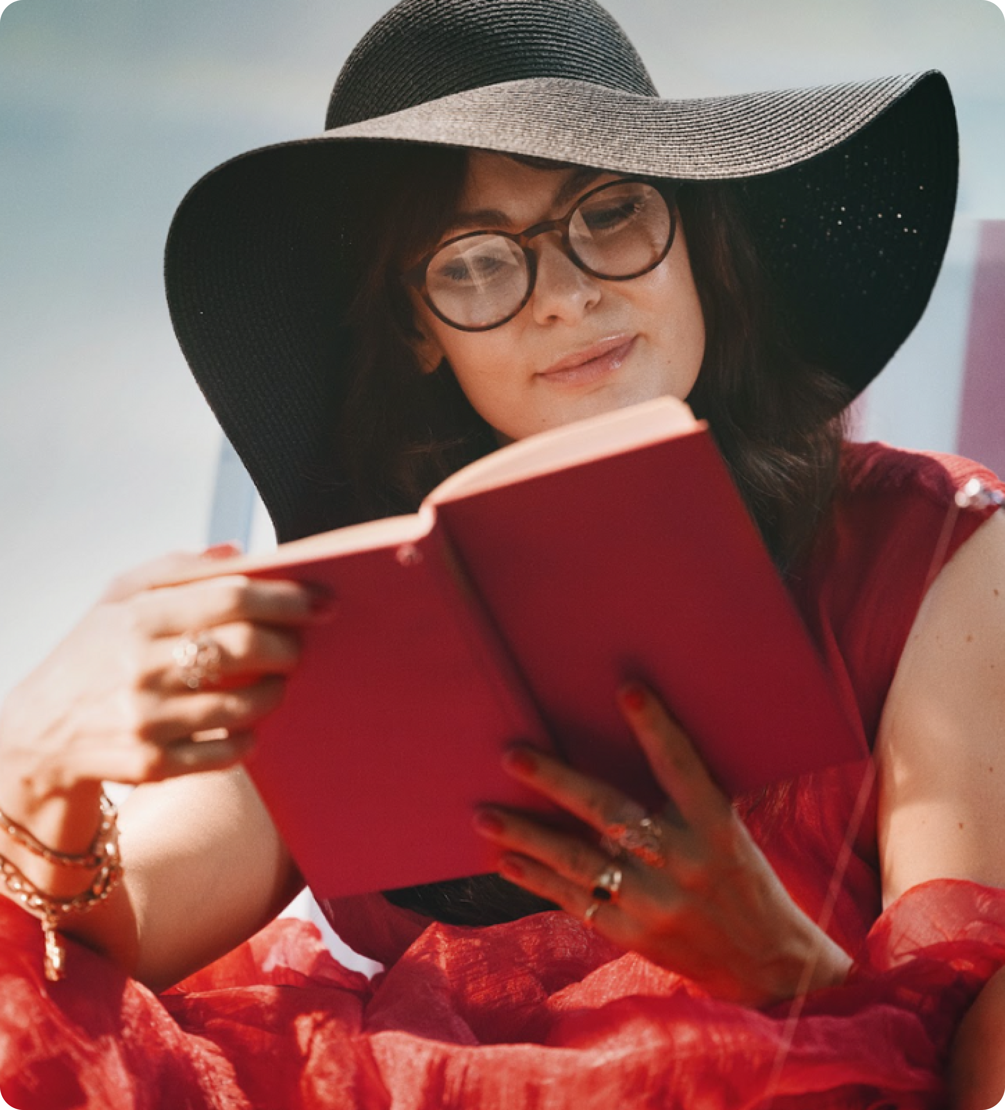 Woman wearing a large black hat and stylish eyeglasses, reading a red book, illustrating the question 'Are you tired of reading glasses from the supermarket with poor quality?